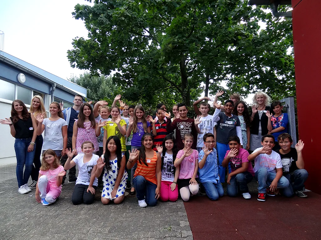 Klassenfoto einer neuen fünften Klasse, die Kinder winken und lachen.